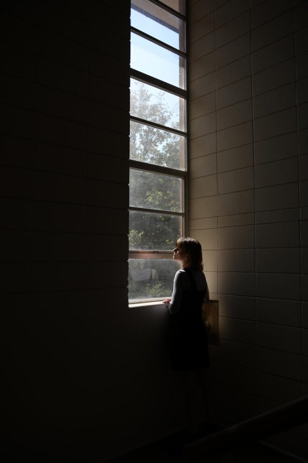 Emily Gift holds onto a window sill as she looks out the University of Texas at Austin’s art building window, Friday, Oct. 22, 2021.
