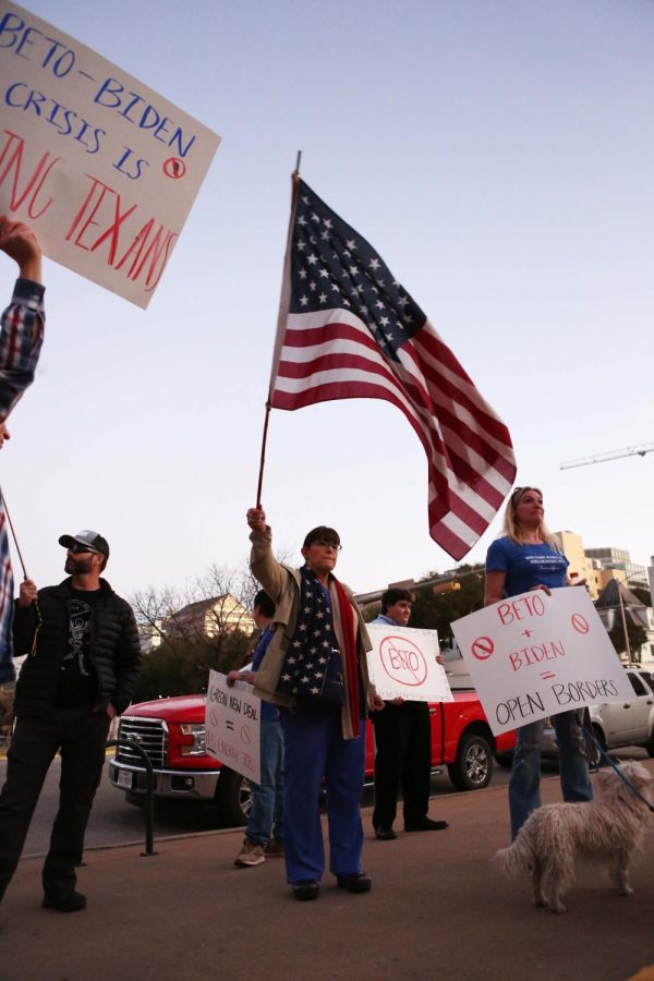 Protestors wave flags and hold signs outside of the Beto ORourke rally.