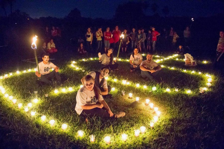 People sit on a lawn in candles that form the shape of 60+