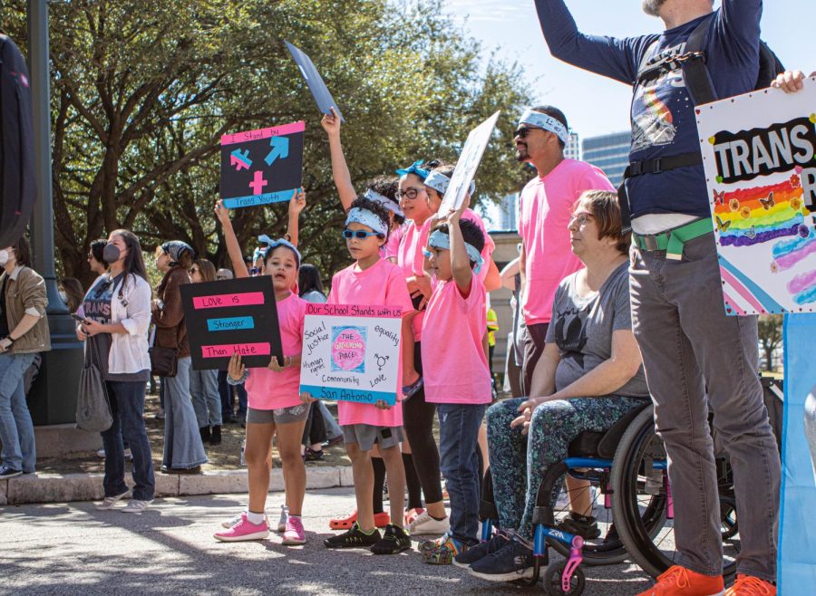 A group of children wave signs in the air to support trans youth. On March 1, hundreds of people protested outside of the Texas state Capitol after Gov. Greg Abbott placed restrictions on trans medical procedures.