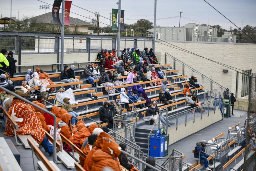 Fans huddle together for warmth as they cheer on Texas softball despite the cold weather.