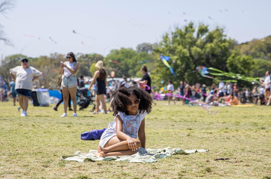 In the heat of Austin’s Kite Fest, a young girl rests on a blanket at Zilker Park after flying a kite. 