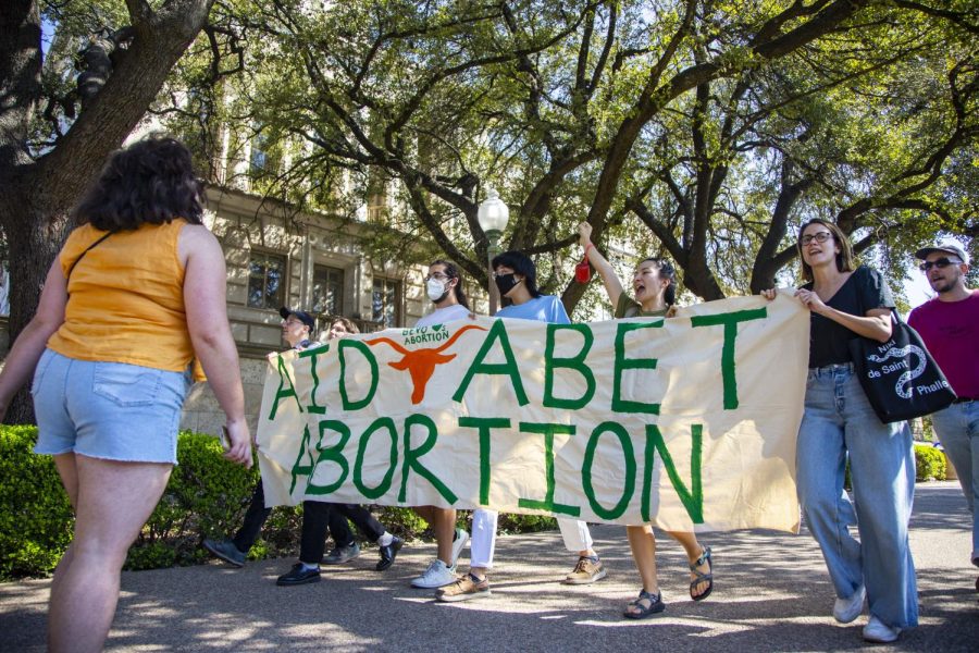 Protesters hold a banner reading AID ABET ABORTION during a protest on the West Mall on Oct. 6, 2022. 