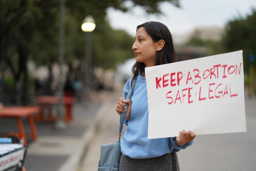 A protestor holds up a sign on Speedway in front of the Perry-Castañeda Library on Oct. 27, 2022.