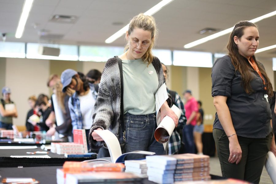 While flipping through pages in line, a COLA Faculty Book Fair customer browses the selection of books available for purchase on Nov. 4 in Patton Hall. Books published within the past two years by COLA faculty were available for free or purchase along with magazines, live music, catering and merchandise.