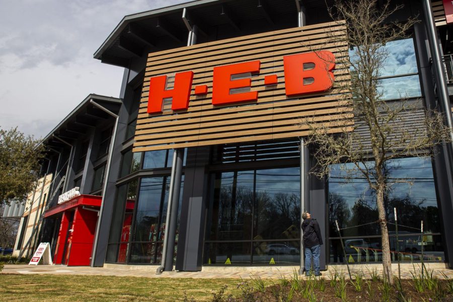 A pedestrian stops and looks upwards at a new H-E-B sign. The Lake Austin location, which opened on Feb. 15, will be the first in Austin to feature two stories.