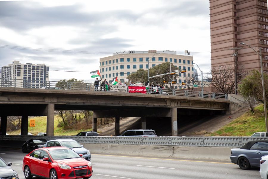 Protestors wave Palestinian flags and hang banners from the 11th St. bridge overlooking I-35 on Jan. 20, one day before the protest against the IAC Summit. 