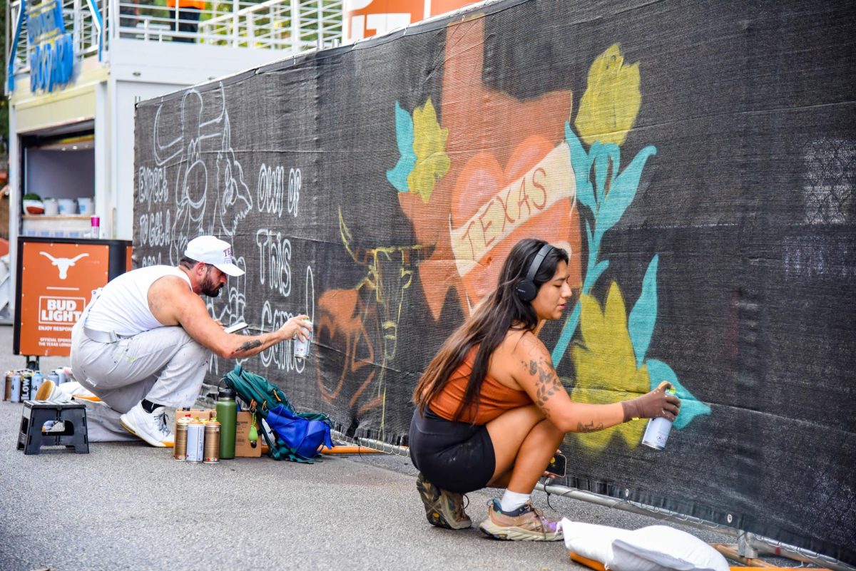 Live painters return to Bevo Boulevard for the first game of the season on September 2, 2023. The artists spray paint murals before the game as people pass and watch.