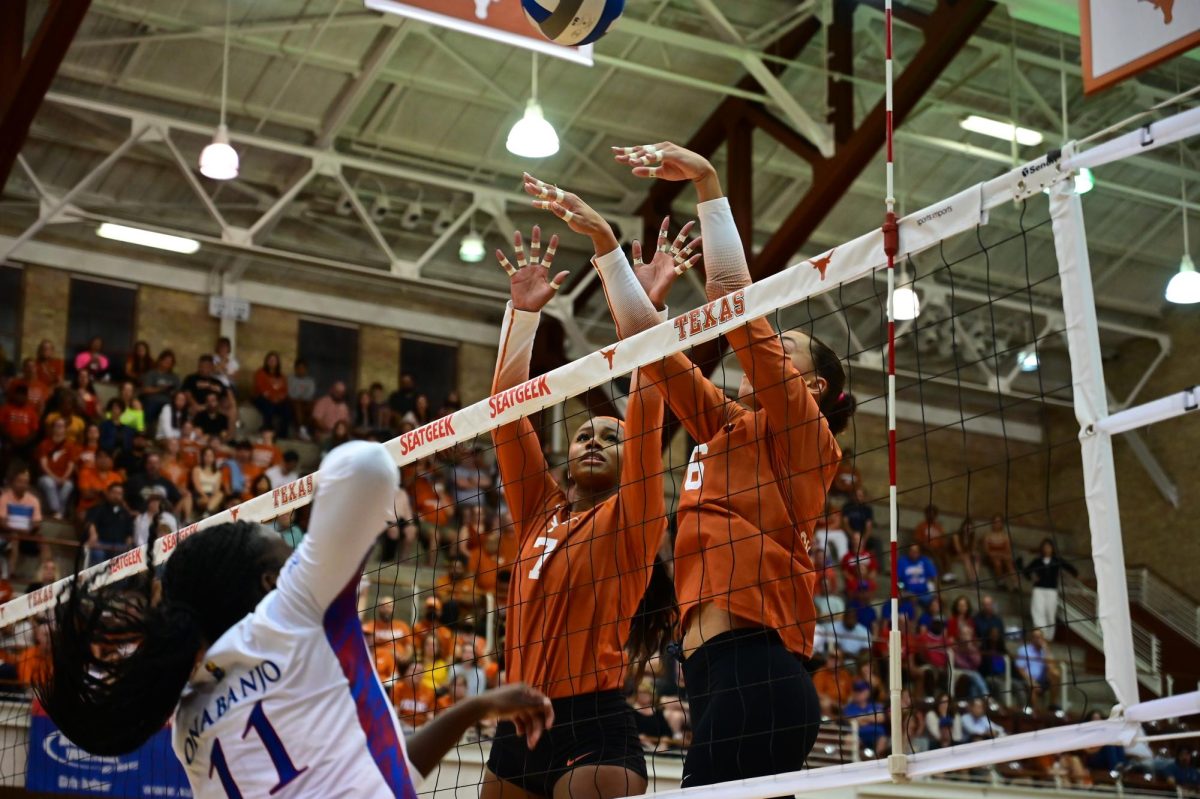Madisen Skinner and Asjia ONeal attempt to block a spike by Toyosi Onabanjo during a game against the University of Kansas on October 6th, 2023