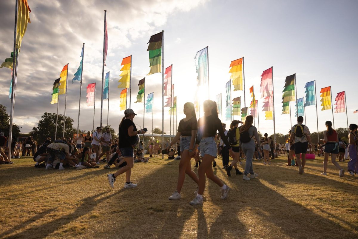 ACL goers walk past the infamous flag poles erected in Zilker Park on Oct. 14, 2023.