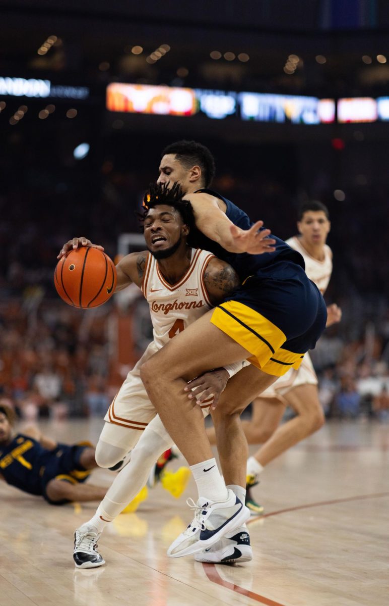 Guard Tyrese Hunter is blocked by a West Virginia player during Texas game against the Mountaineers on Feb. 10, 2024.