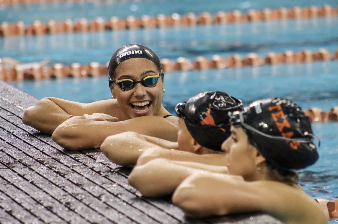 Fifth-year Kelly Pash laughs with her teammates as they watch the ongoing races on Oct. 6, 2023. At this meet against the University of Houston, Pash competed in the 400-yard freestyle relay.