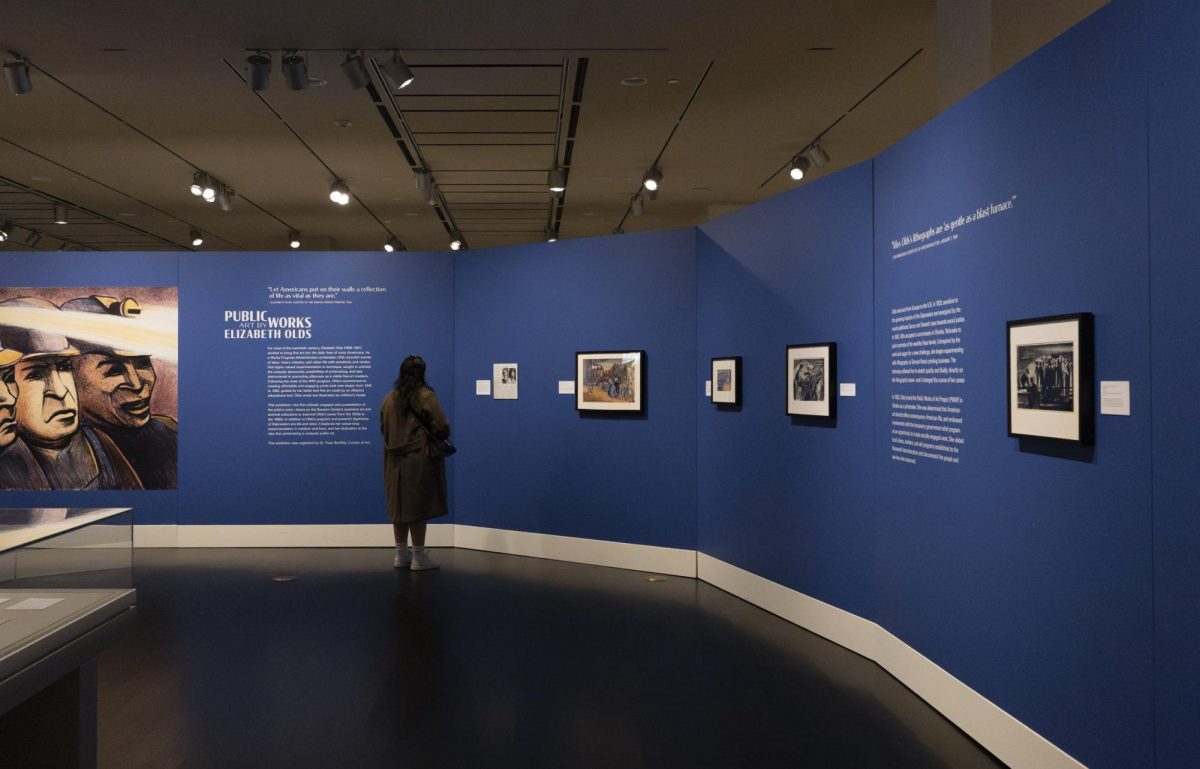 A visitor walks through the exhibition Public Works: Art by Elizabeth Olds at the Harry Ransom Center on Wednesday. From depictions of Depression-era America to captivating childrens books, the exhibition contains over 100 prints, paintings and illustrations that explore Olds artistic legacy. To the left is an image of her color lithograph titled Miners from 1937. 