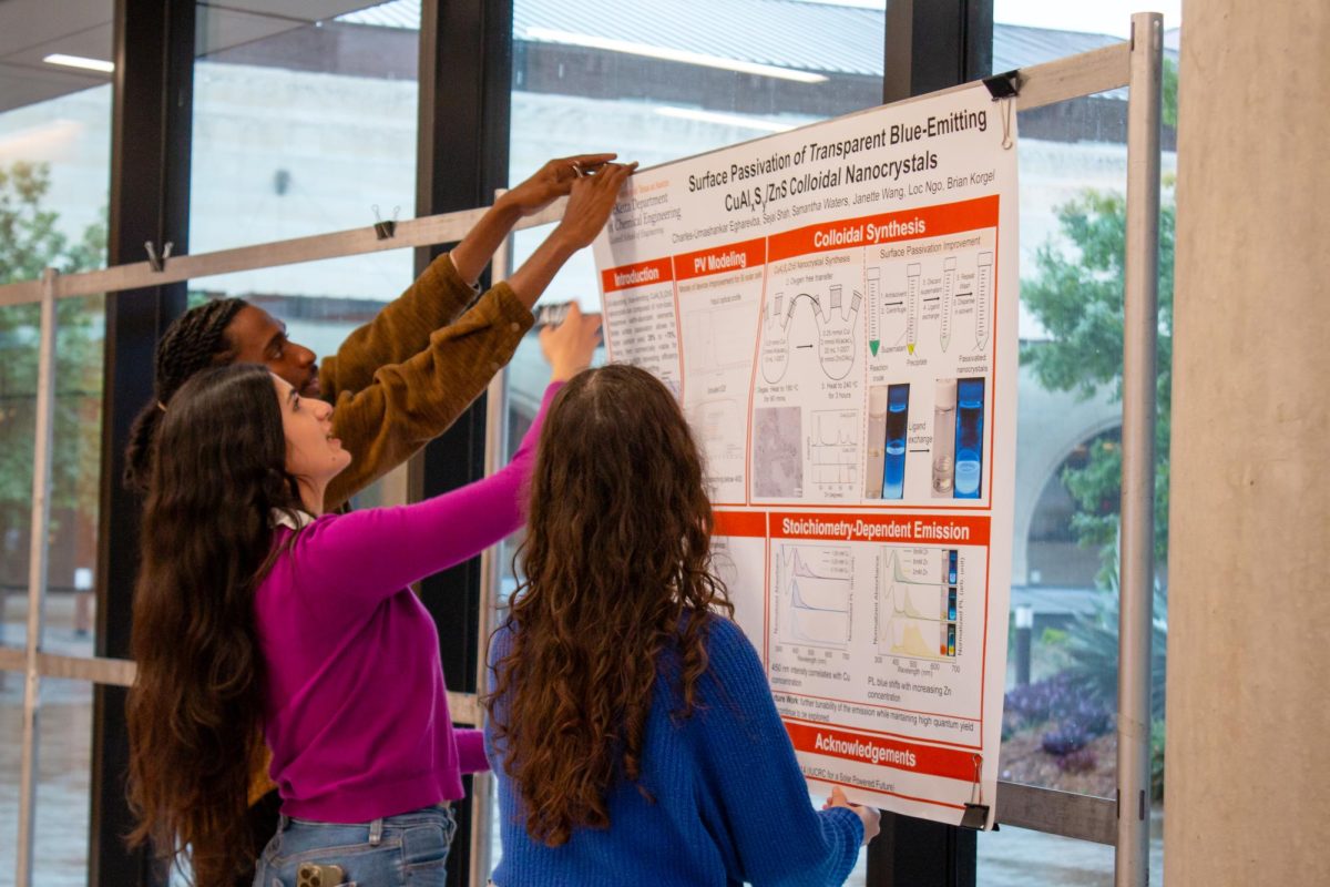 Graduate students Charles-Umashankar Egharevba (left) and Sejal Shah (middle) hang up their presentation highlighting the applications of nanomaterials in the energy sector during Willow Energy Week on March 27, 2024.