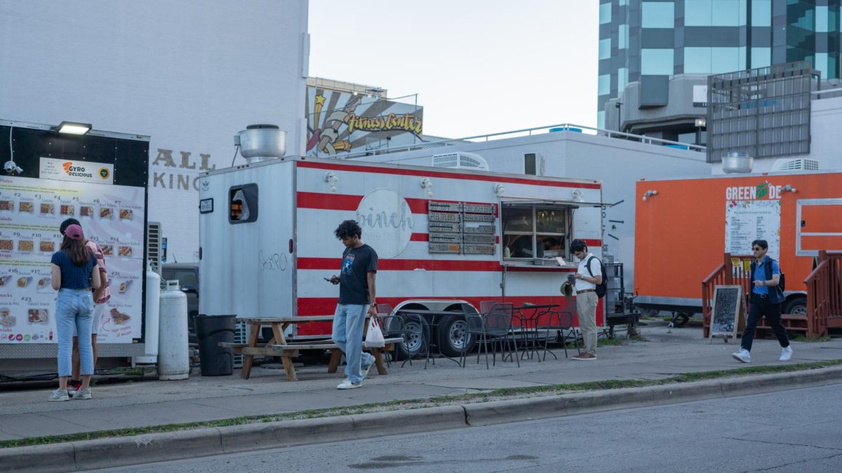 Pedestrians walk in front of the food trucks on 21st Street on Wednesday. 
