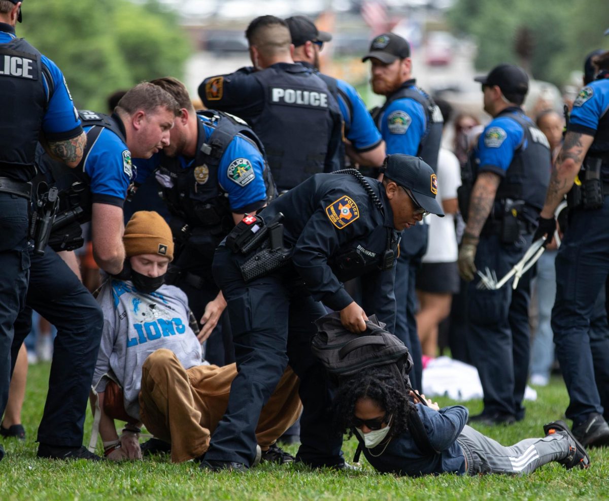 Police arrest two people on the South Lawn during the protest on Wednesday while holding them by their shirt collars and backpacks.