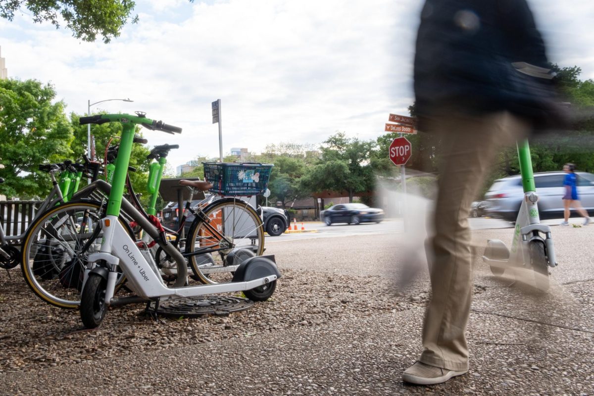 A pedestrian walks by a rack of lime scooters on San Jacinto Boulevard in Austin, Texas on April 10, 2024. 