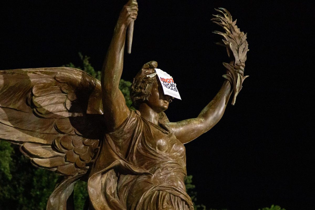 A Not Our Texas sign is pictured on the Littlefield Fountain statue on Thursday. Students posted hundreds of flyers on campus and West Campus past midnight.