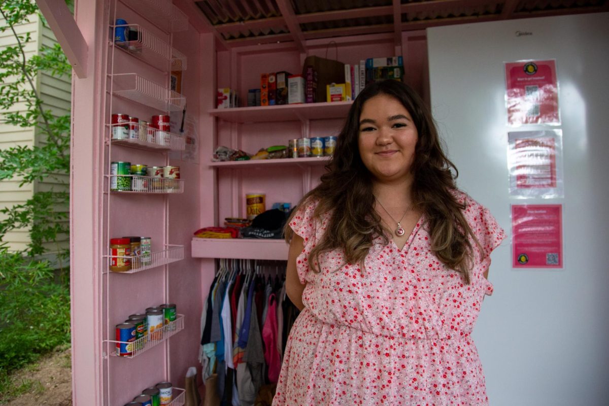 Maya Crane, a government and Mexican American and Latino studies sophomore, is pictured in front of the West Campus free fridge on April 6, 2024. Crane and a group of volunteers built and installed the structure behind Pearl Street Co-op.