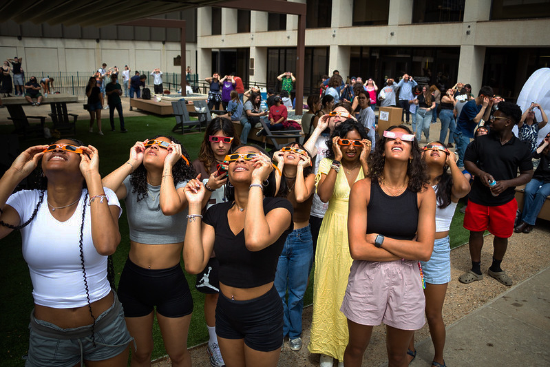 Crowds look to the partial eclipse with solar eclipse glasses provided by U.T Austin at the Walter Cronkite Plaza on April 8, 2024.