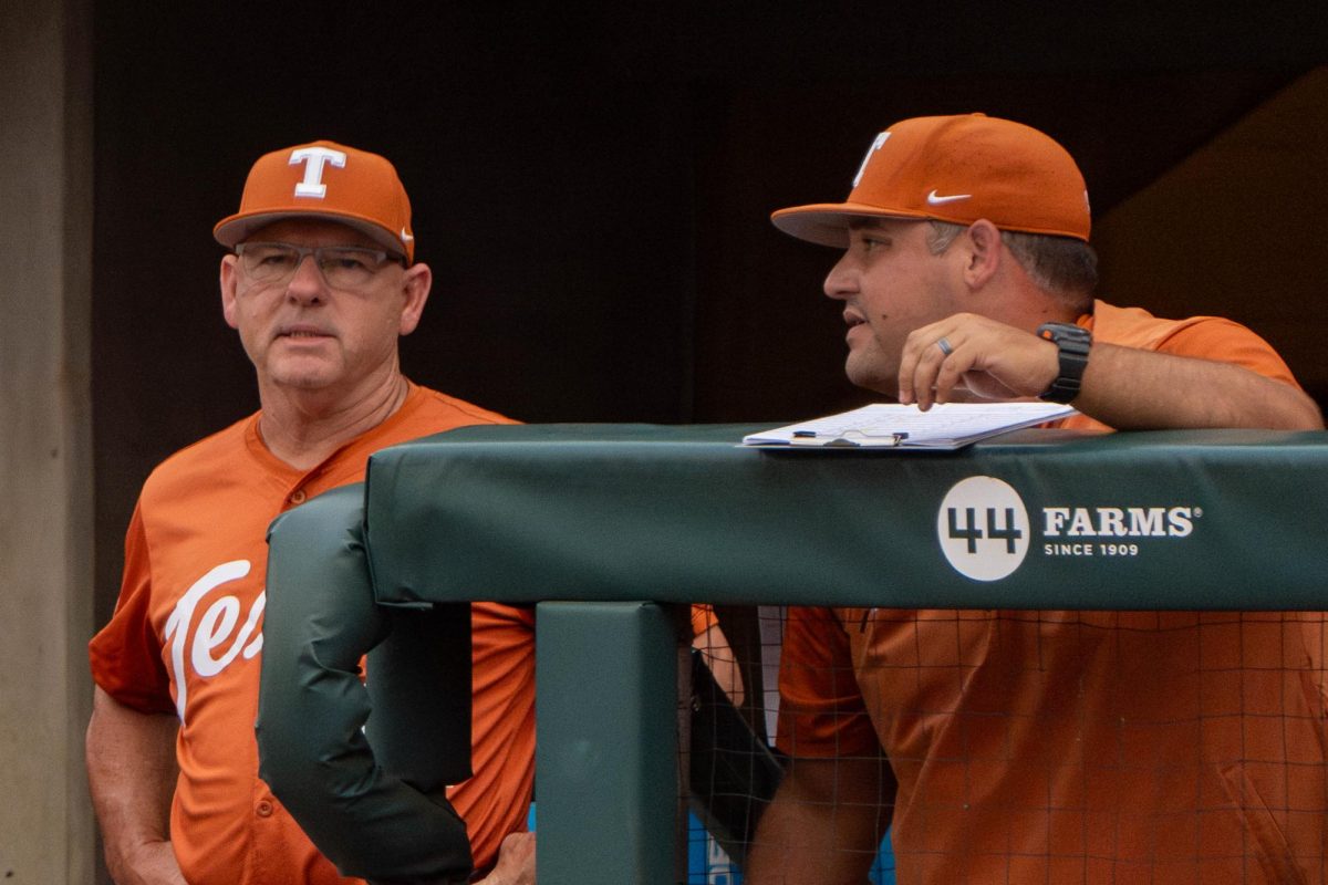 Head baseball coach David Pierce talks to hitting and pitching development coach Chris Gordon in the dugout during Texas regional tournament game against Louisiana on May 31, 2024.
