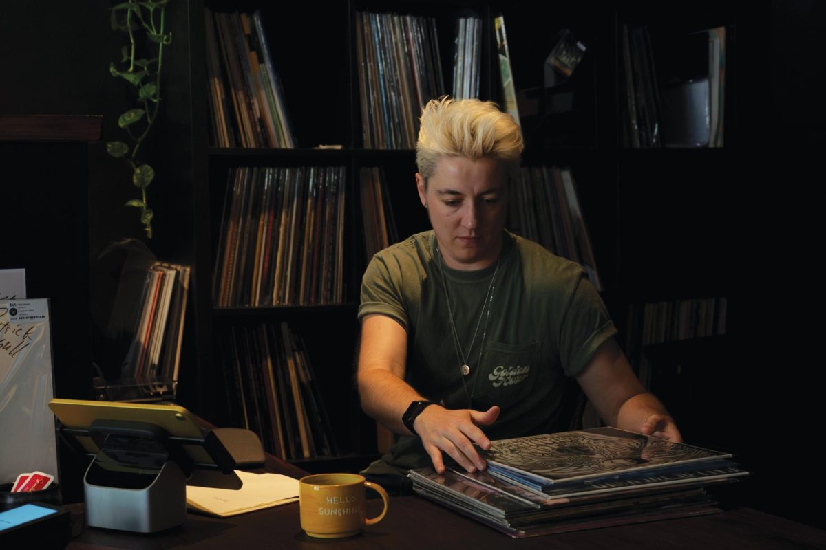 Owner Luca Kisielius poses for a portrait at their desk inside Sunshine Vinyl on Saturday.