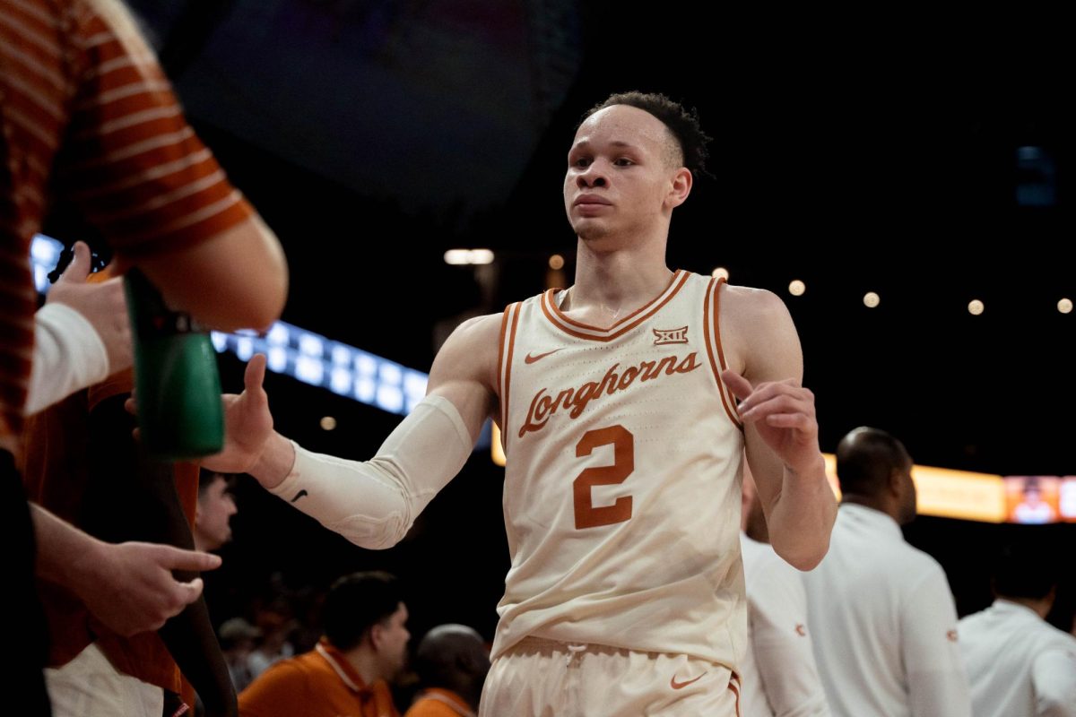 Guard Chendall Weaver high fives his teammates on the bench during Texas' game against OSU in the Moody Center on March 2, 2024.