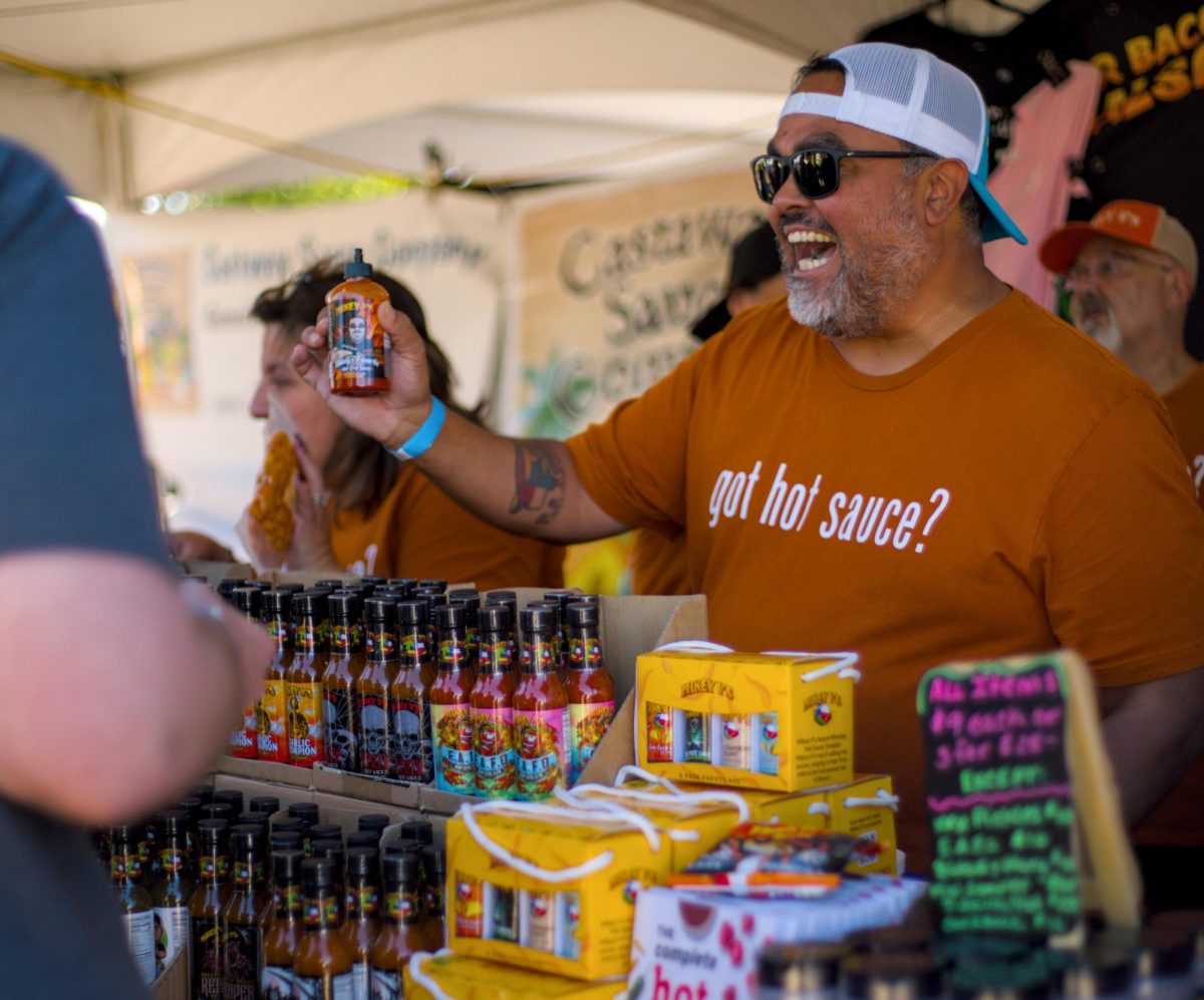 Michael Valencia, owner of Mikey V's hot sauce, serves samples of his hot sauce at the hot sauce festival hosted by the Austin Chronicle on Sept. 8.