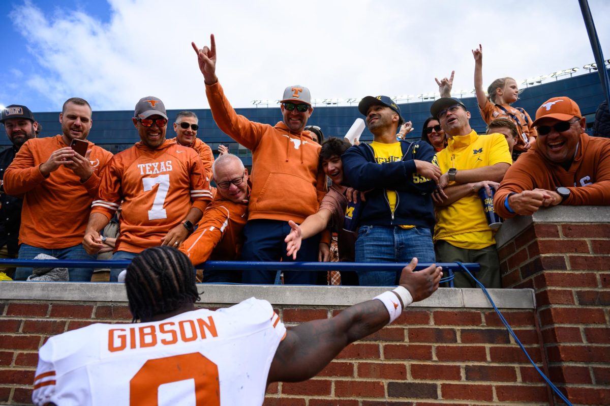 Texas running back Jerrick Gibson high fives a fan after the Texas vs. Michigan Football game at Michigan Stadium on Saturday. Texas won 31-12.