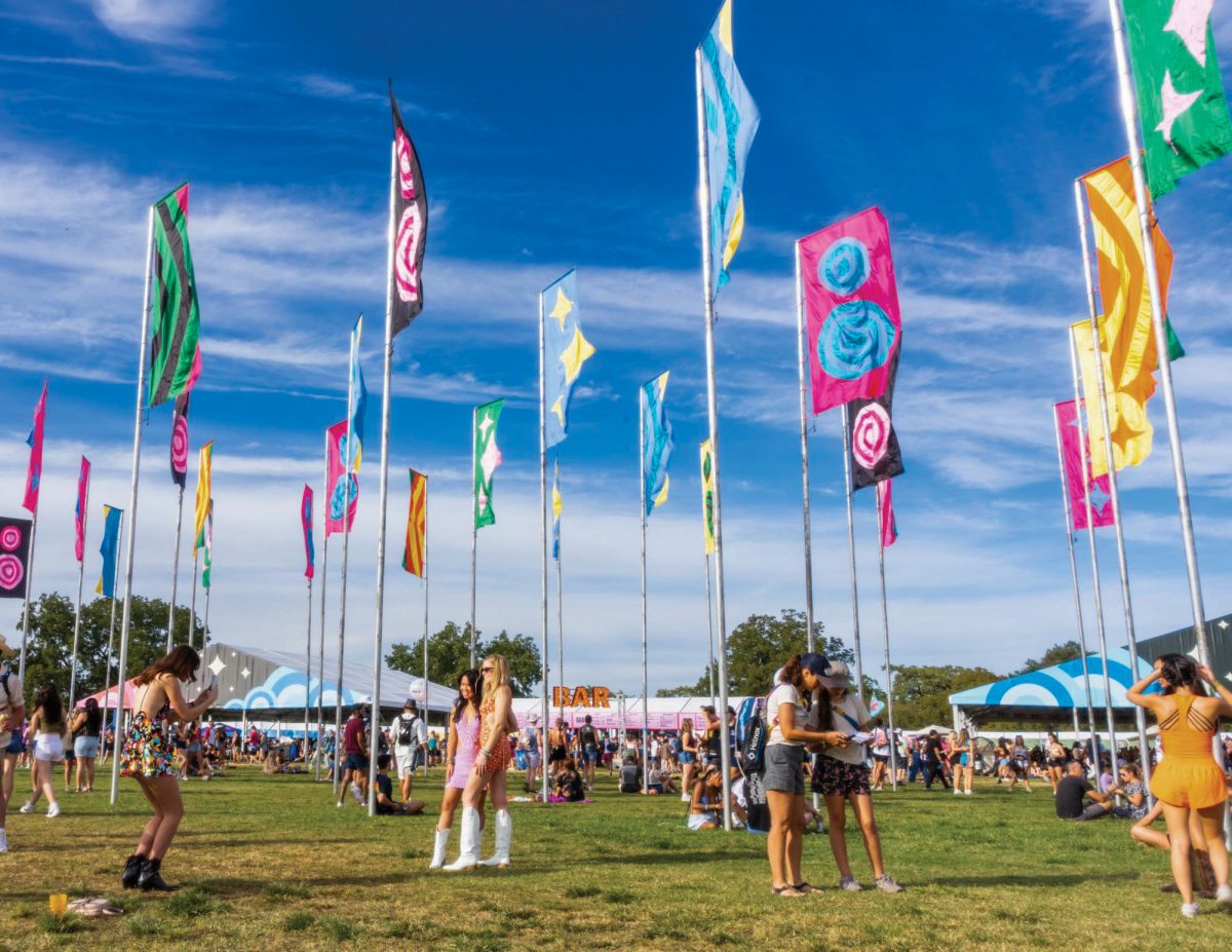 Austin City Limit attendees pose in front of the iconic flag poles that are erected each year in Zilker Park on October 6, 2023.