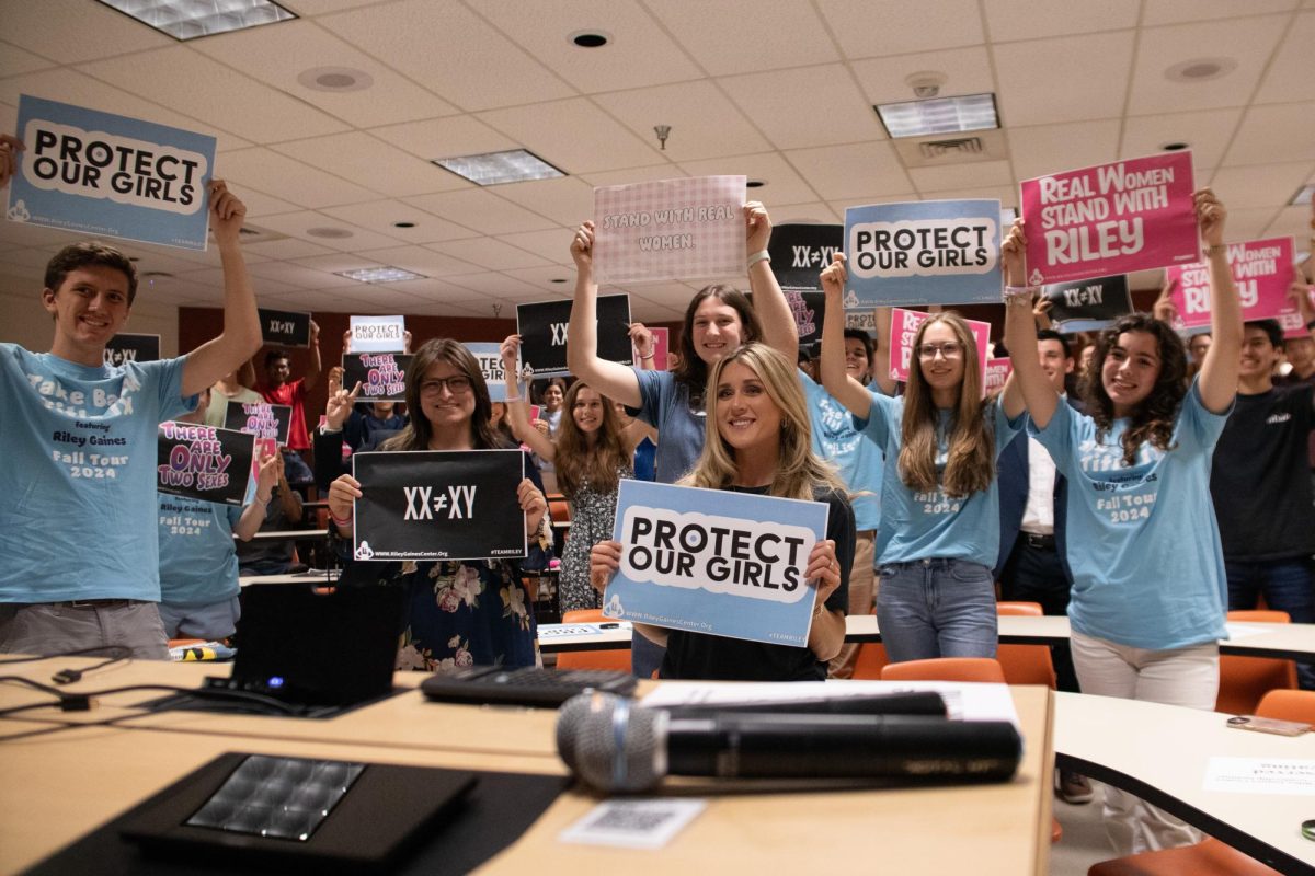 Riley Gaines holds up a sign with an audience at the Young Conservatives meeting on Oct. 3, 2024.