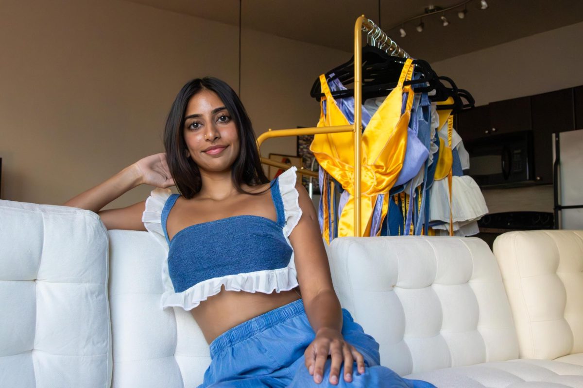 Pranisha Karuturi, founder and owner of By Pranisha, a sustainable clothing brand, smiles in her Austin apartment while wearing a design from her "Bloom" collection on Oct. 7, 2024. Karuturi is a UT class of 2022 graduate owns and a member of the UT Kendra Scott Women's Entrepreneurial Leadership Institute and FoundHER program.