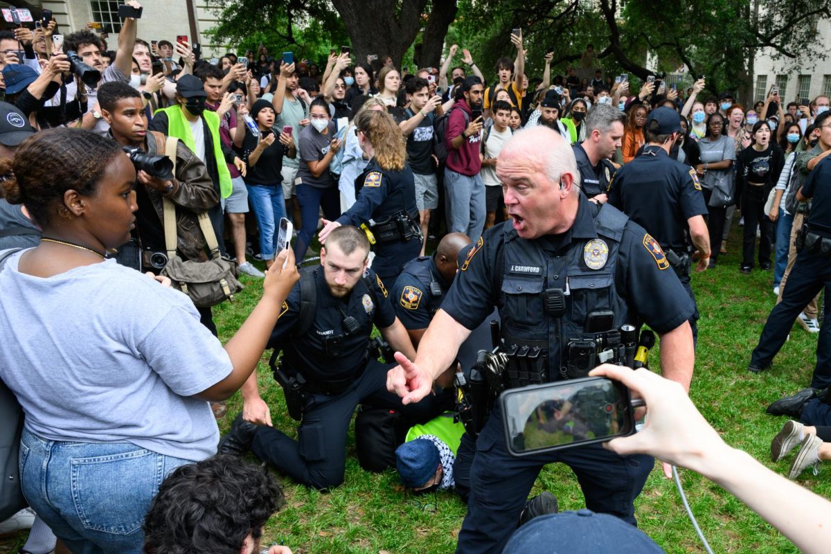 A police officer warns protesters to make space as an organizer is held down and zip-tied on UT's Main Mall during the pro-Palestine student walkout on Wednesday, April 24, 2024.