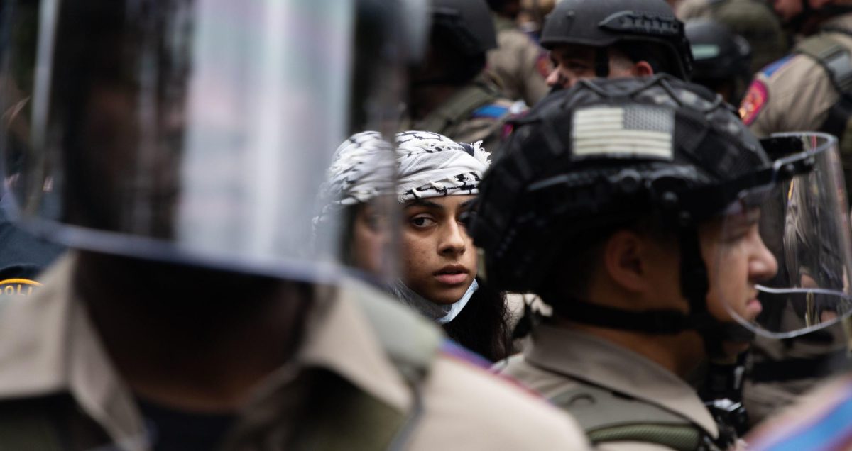 A protester stands amongst state troopers after being arrested during a protest on the University of Texas campus on April 24, 2024.