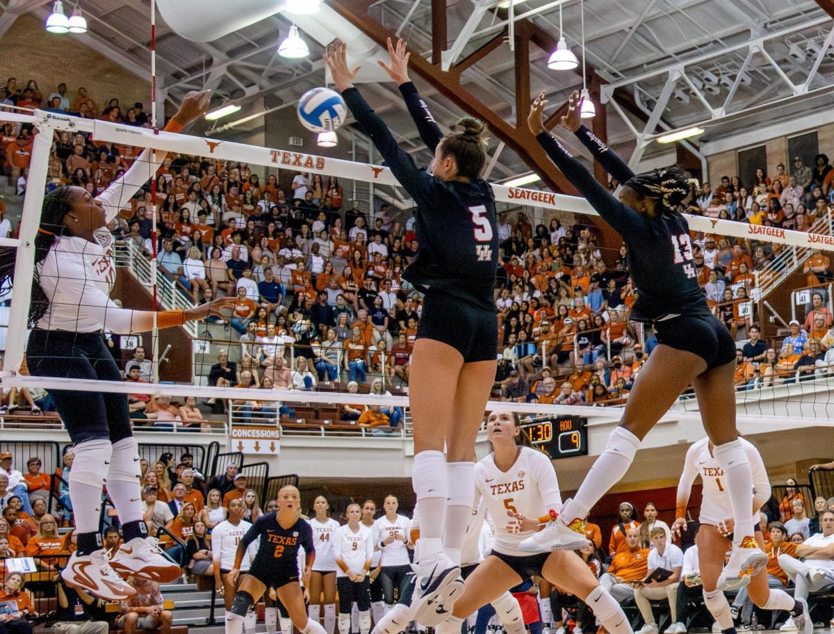 Reagan Rutherford spikes the ball while Lily Barron (left) and Barakat Rahmon (right) attempt to block the ball during the UT vs. Houston match on Sept. 11, 2024.