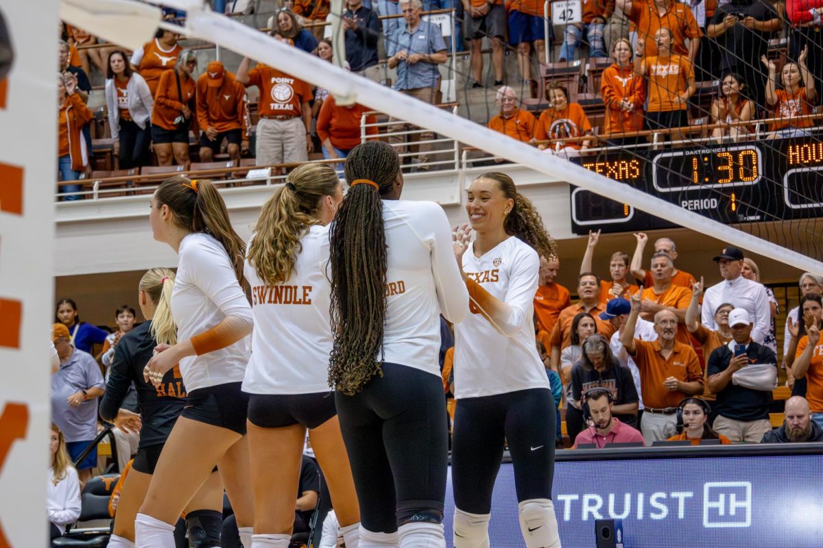 Madisen Skinner high-fives teammates Ella Swindle and Reagan Rutherford after the team earned their first point in the match against Houston on Sept. 11, 2024. The Longhorns won 25-20.