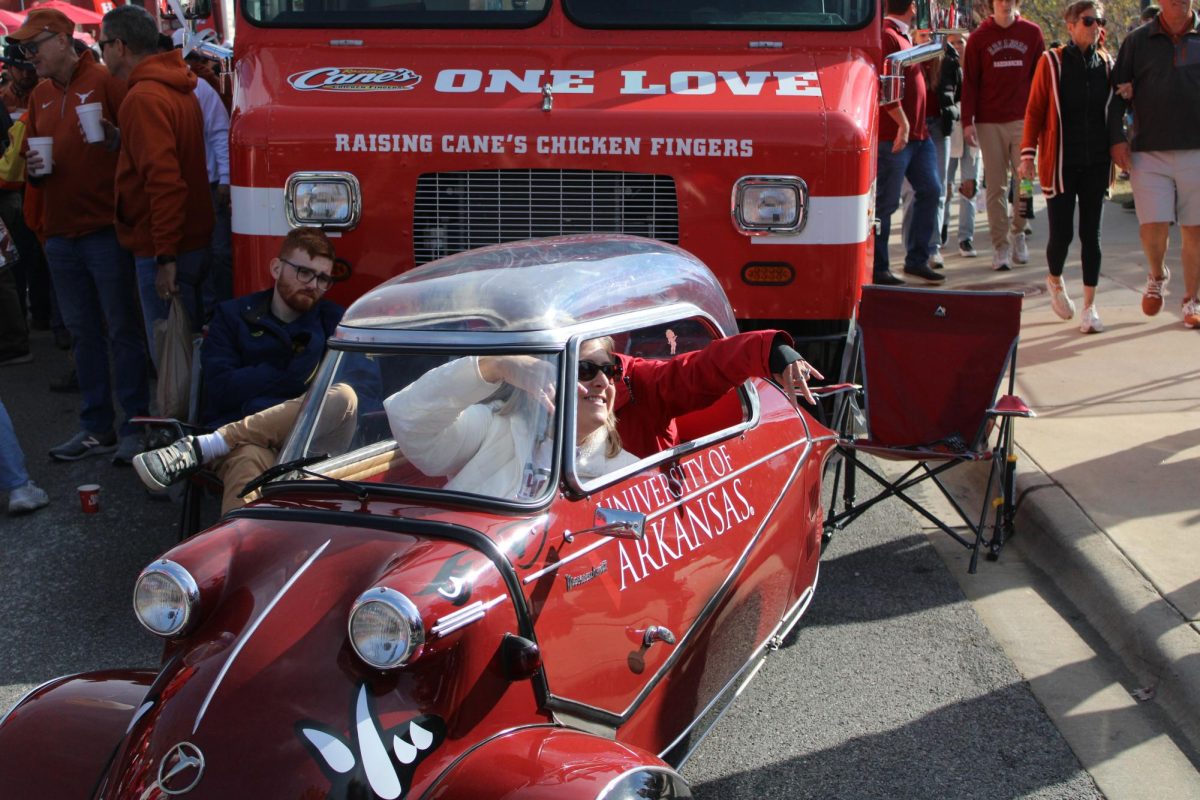 Fans pose with a 'horns down' symbol inside of a decorated antique car before the Texas-Arkansas game on Nov. 16, 2024. 