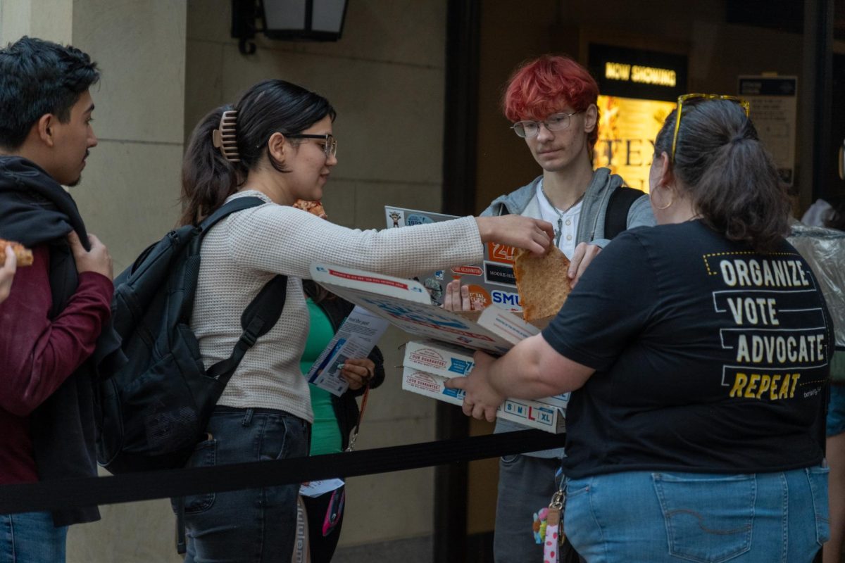 An organizer hands out pizza to voters in line on Nov. 5, 2024.