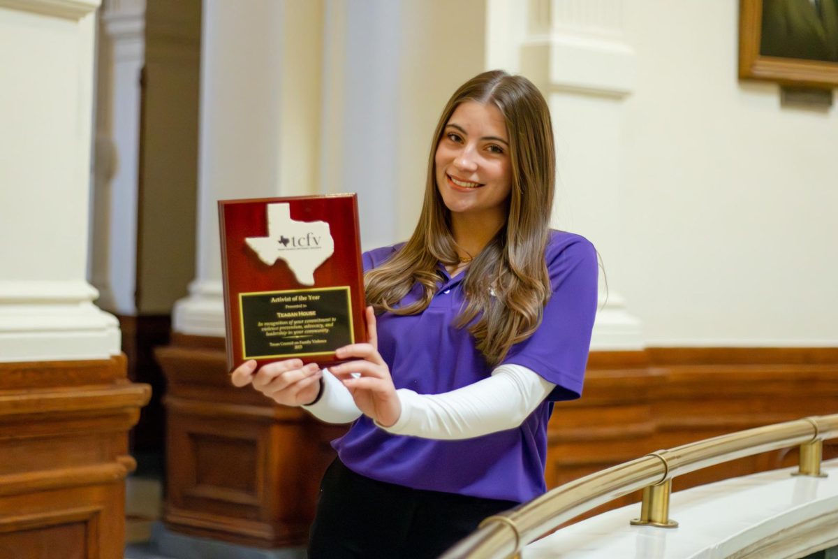 Teagan House, named activist of the year by the Texas Council on Family Violence, stands with her placard inside the Texas State Capitol on Feb. 20, 2025.