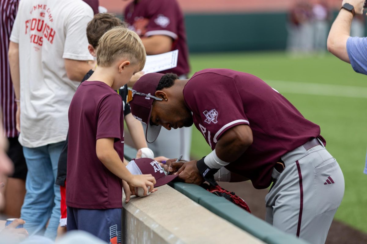 Texas A&M utility player Jamal George signs a hat for a fan during the final game in the series against Texas on April 27, 2025. 