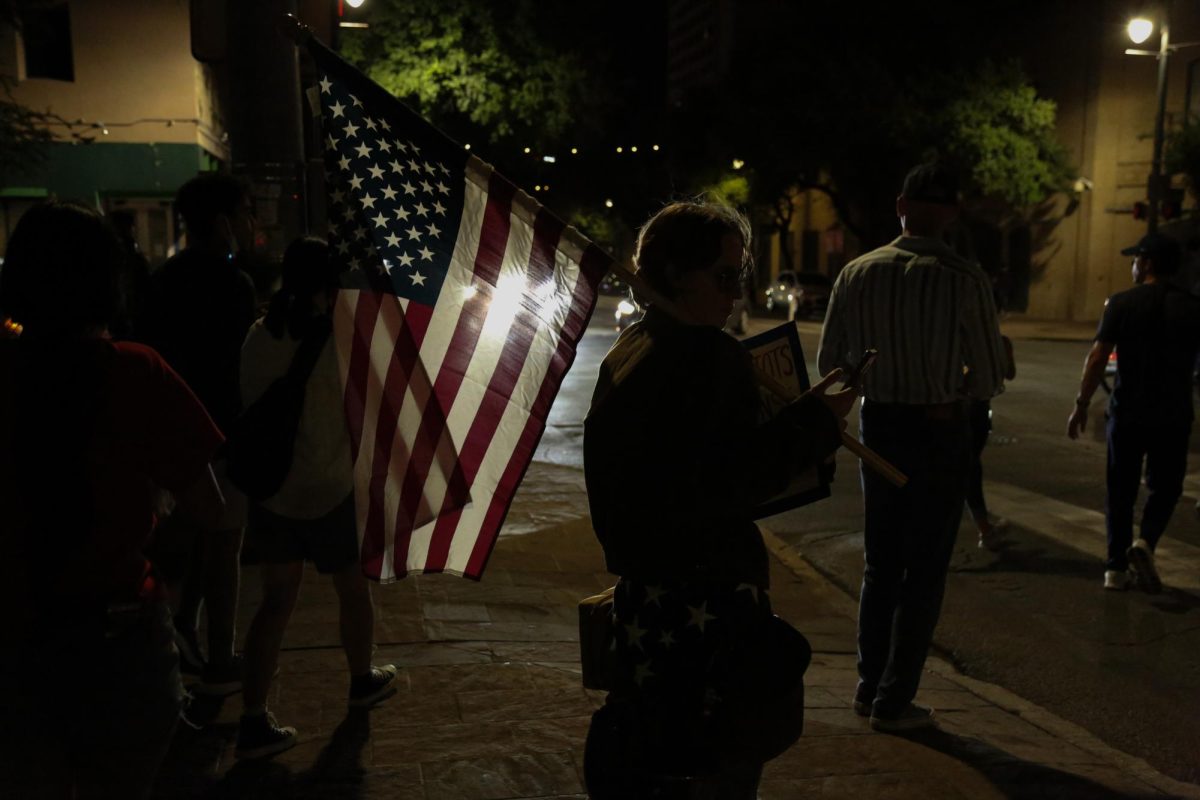 A person holds the American flag on the streets of Austin, Texas as the events of the No Kings Day protest wrap up on June 14, 2025. 