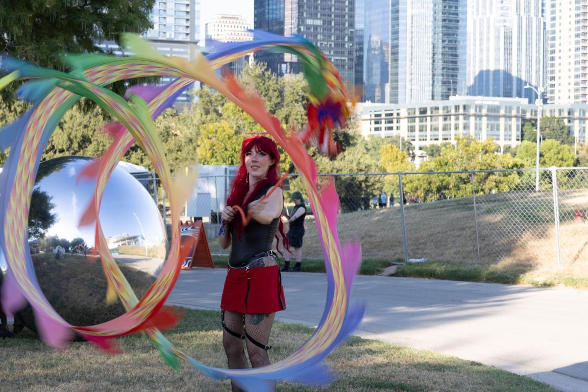 A woman twirls around a rainbow ribbon outside during the Levitation music festival at the Palmer Events Center on Sept. 27, 2025.