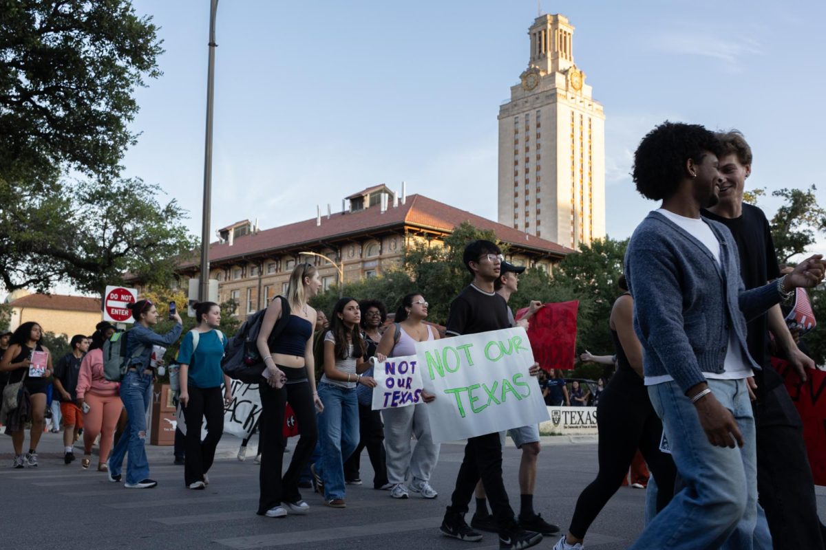 Protesters march around the UT campus with signs on Oct. 22, 2025.