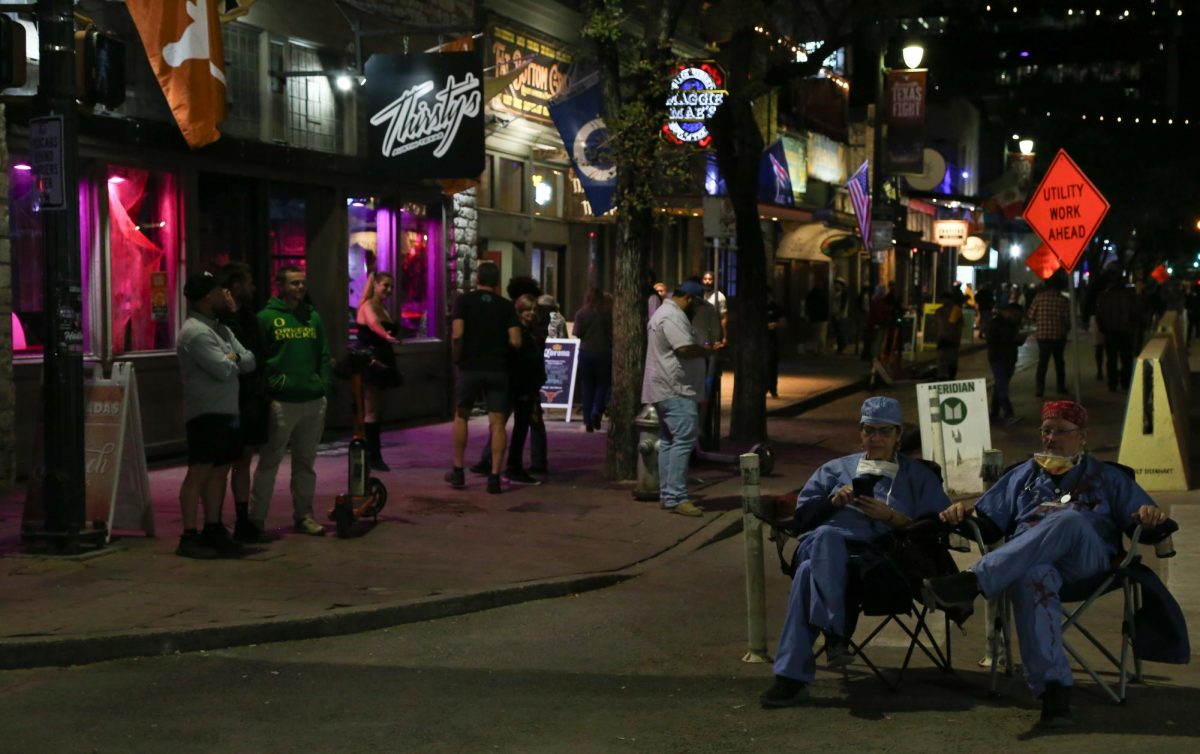 People dressed as doctors sit on Sixth Street during the night of Oct. 31, 2025.