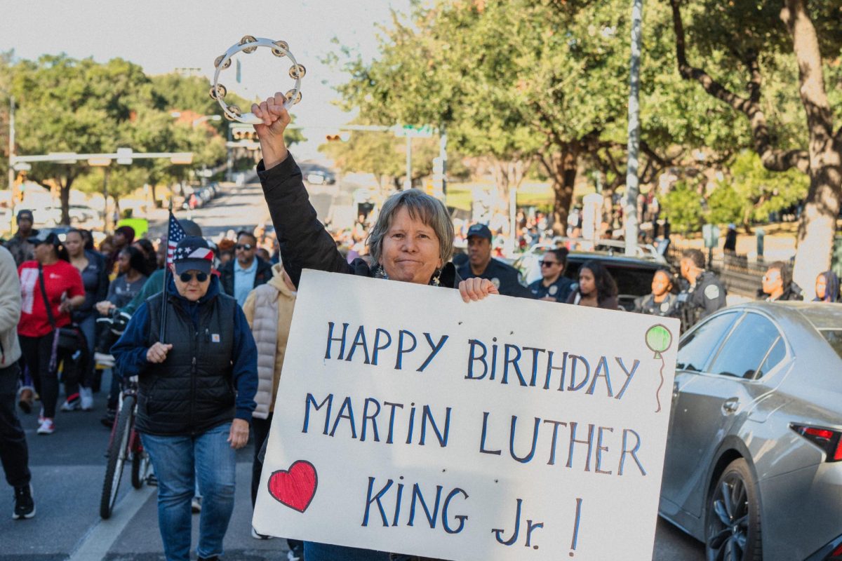 A marcher carries a poster and tambourine at the Dr. Martin Luther King Jr. parade on January 19, 2026.