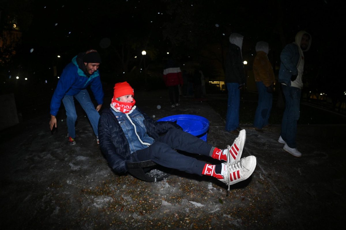 Linguistics and Middle Eastern Studies sophomore Zaniel Moreno pushes Liam McCabe downhill inside of a recycling bin lid on campus on Jan. 24.