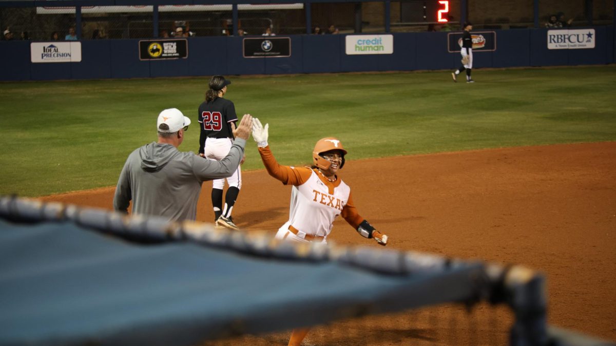 Freshman infielder MaTaia Lawson high-fives a Texas coach as she runs past third to come home for a run during Texas' game against Nebraska in San Antonio Feb. 6.