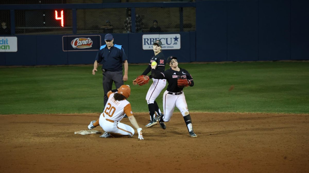 Senior infielder Ava Kuszac throws a ball to first after Texas junior catcher/infielder Katie Stewart slid back into second during Texas' game against Nebraska in San Antonio, Texas, on Feb. 6.