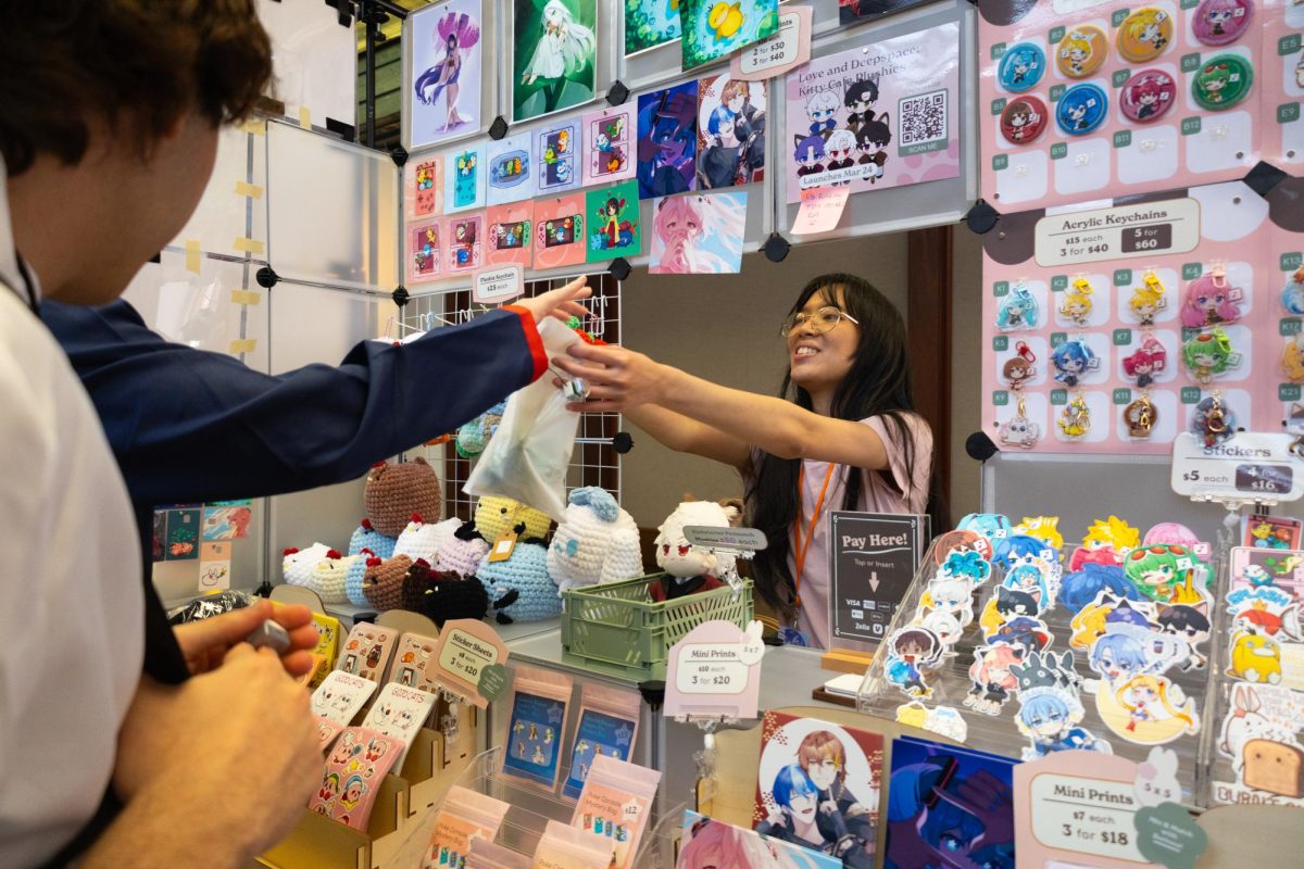 Yookiartstudio vendor Megan Wee Tom makes a sale at KomoriCon's Artist Alley on Feb. 7.