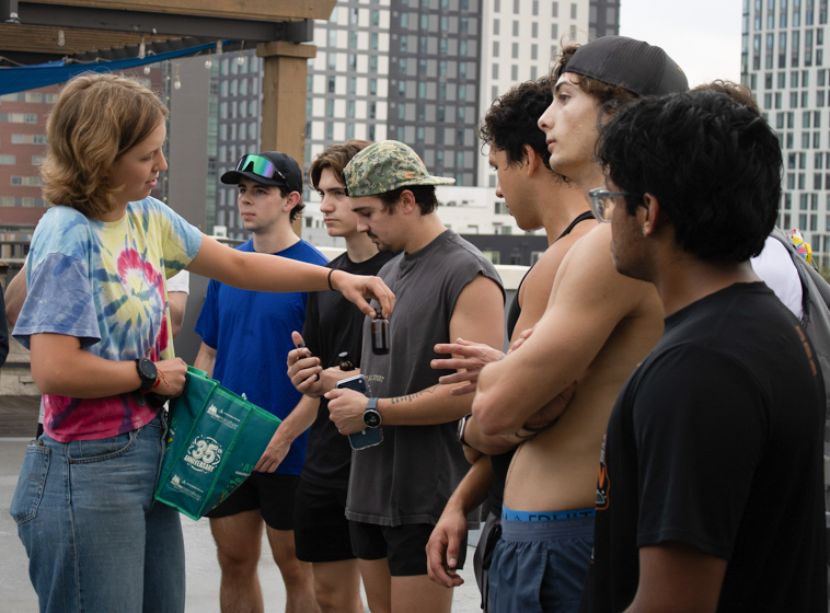 Catie Nunn, Saja Drink co-founder and exercise science senior, hands out bottles of espresso to members of Texas Hybrid at the Block on 25th rooftop on March 5.  